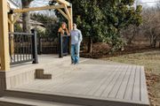 A narrow stone walkway flanked by concrete planter boxes and hedge rows with gravel strips on both sides.