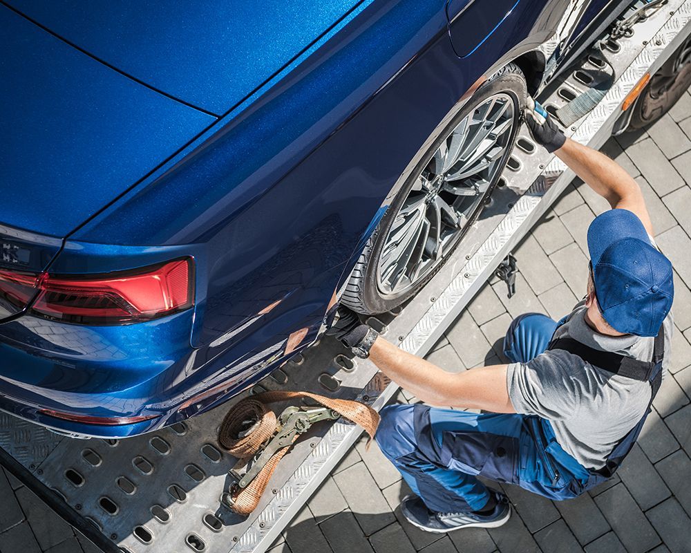 Man is Working on a Blue Car on a Tow Truck