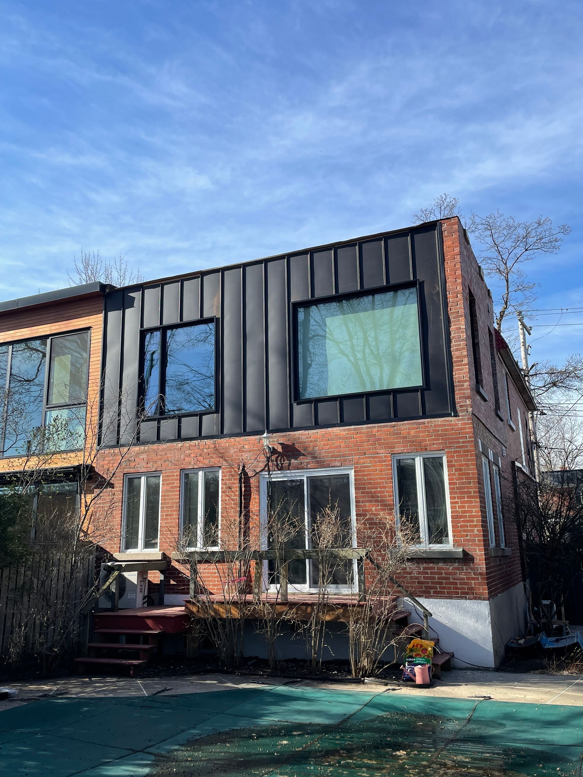 Une grande maison en briques avec un toit noir et beaucoup de fenêtres