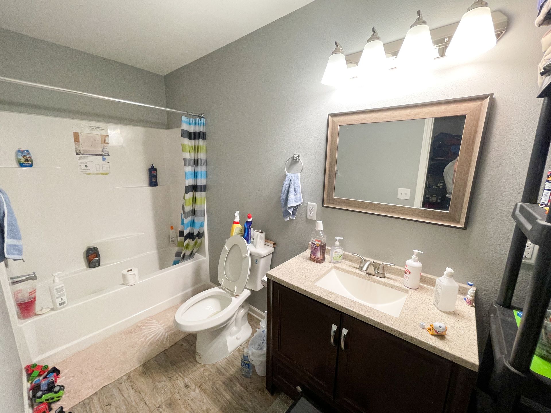 Bathroom with a bathtub, toilet, vanity sink, mirror, and bright overhead lights