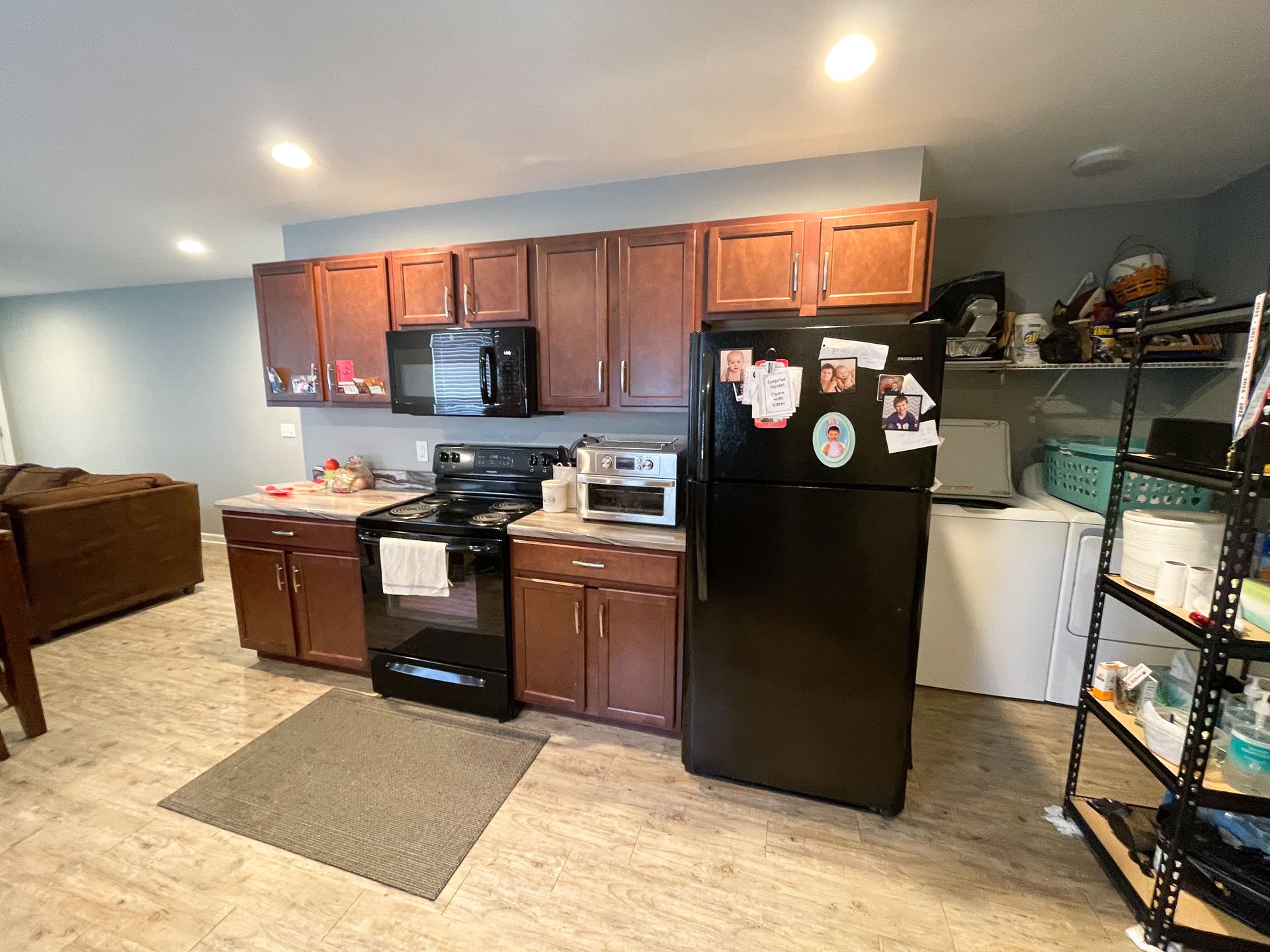 Kitchen with brown cabinets, black appliances, and a laundry area on the right.