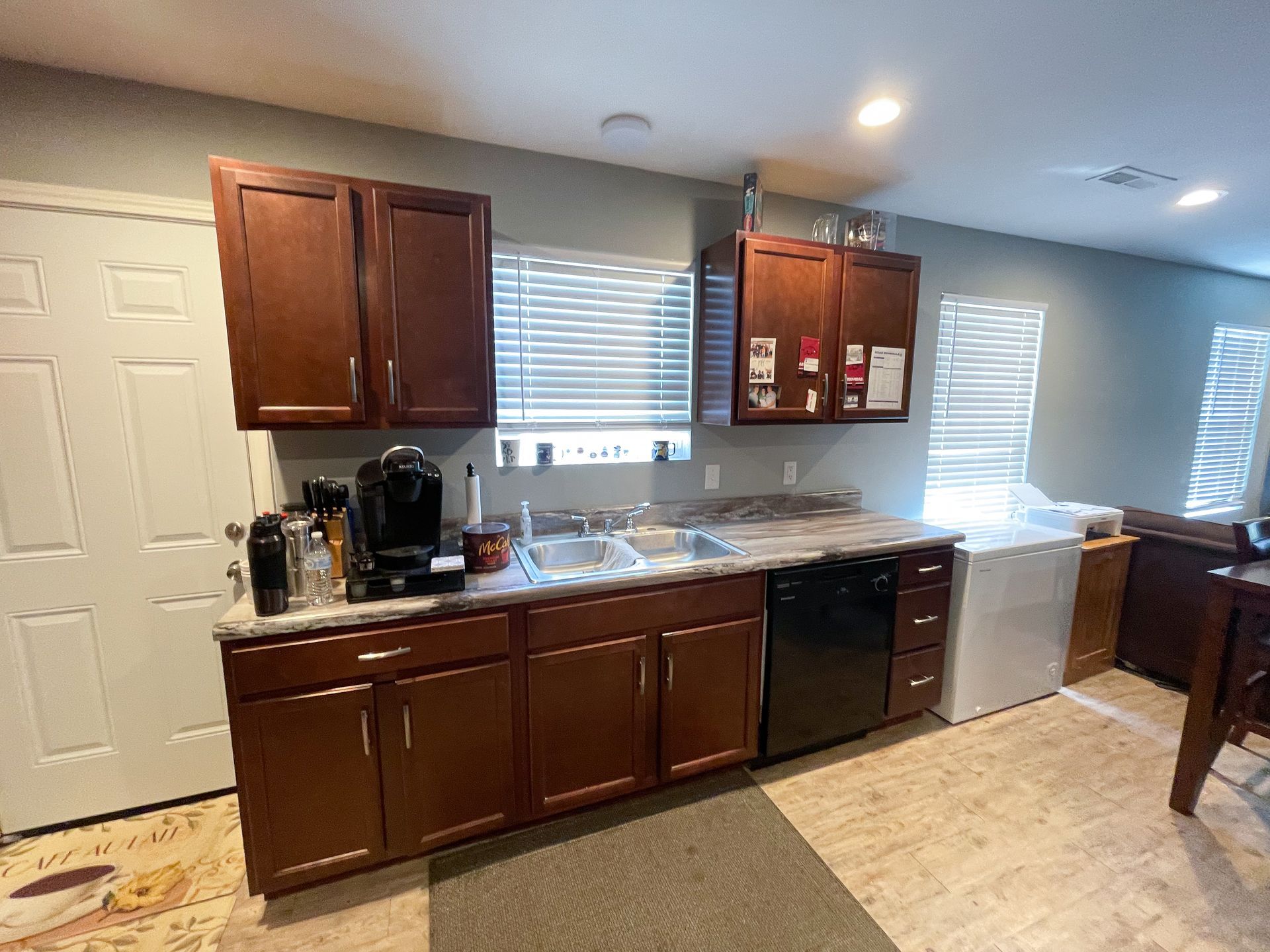 Kitchen with dark wood cabinets, stainless dishwasher, granite counters, and a coffee maker by the sink.