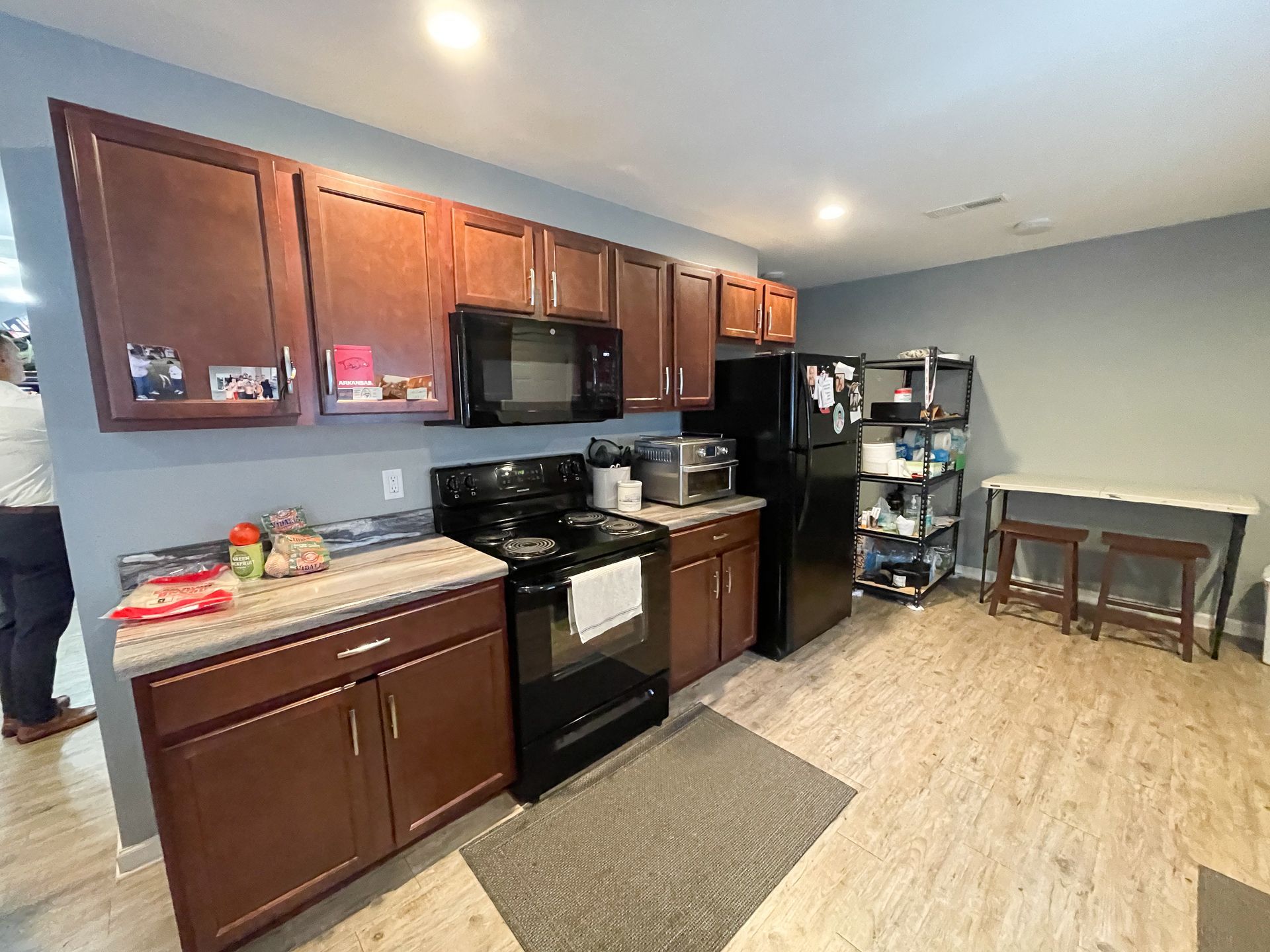 Small kitchen with dark wood cabinets, black appliances, and a dining table by the wall.