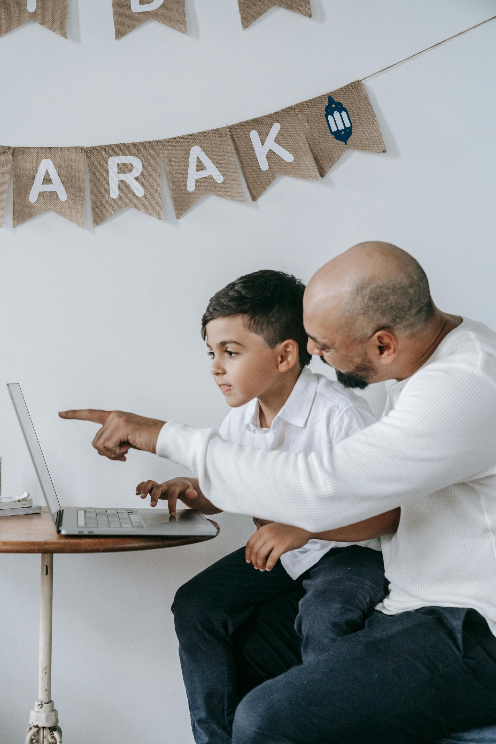 Father and son looking at a laptop together, the father pointing, banner says 