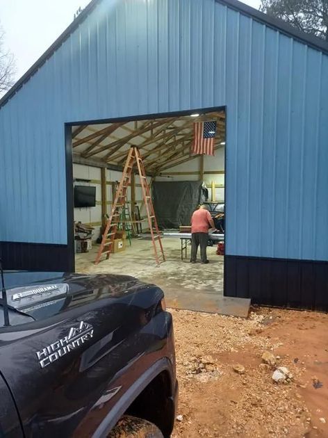 A black truck is parked in front of a blue garage door.