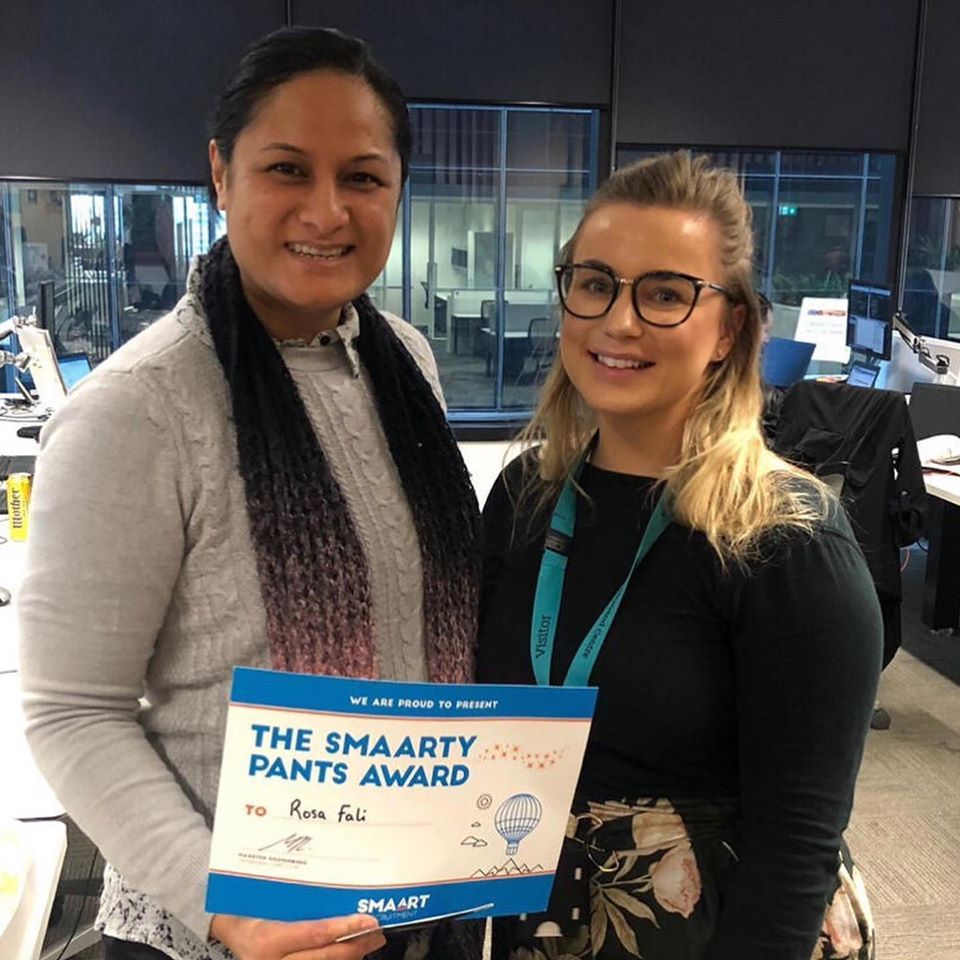 Two women standing next to each other holding a sign that says the smaarty pants award