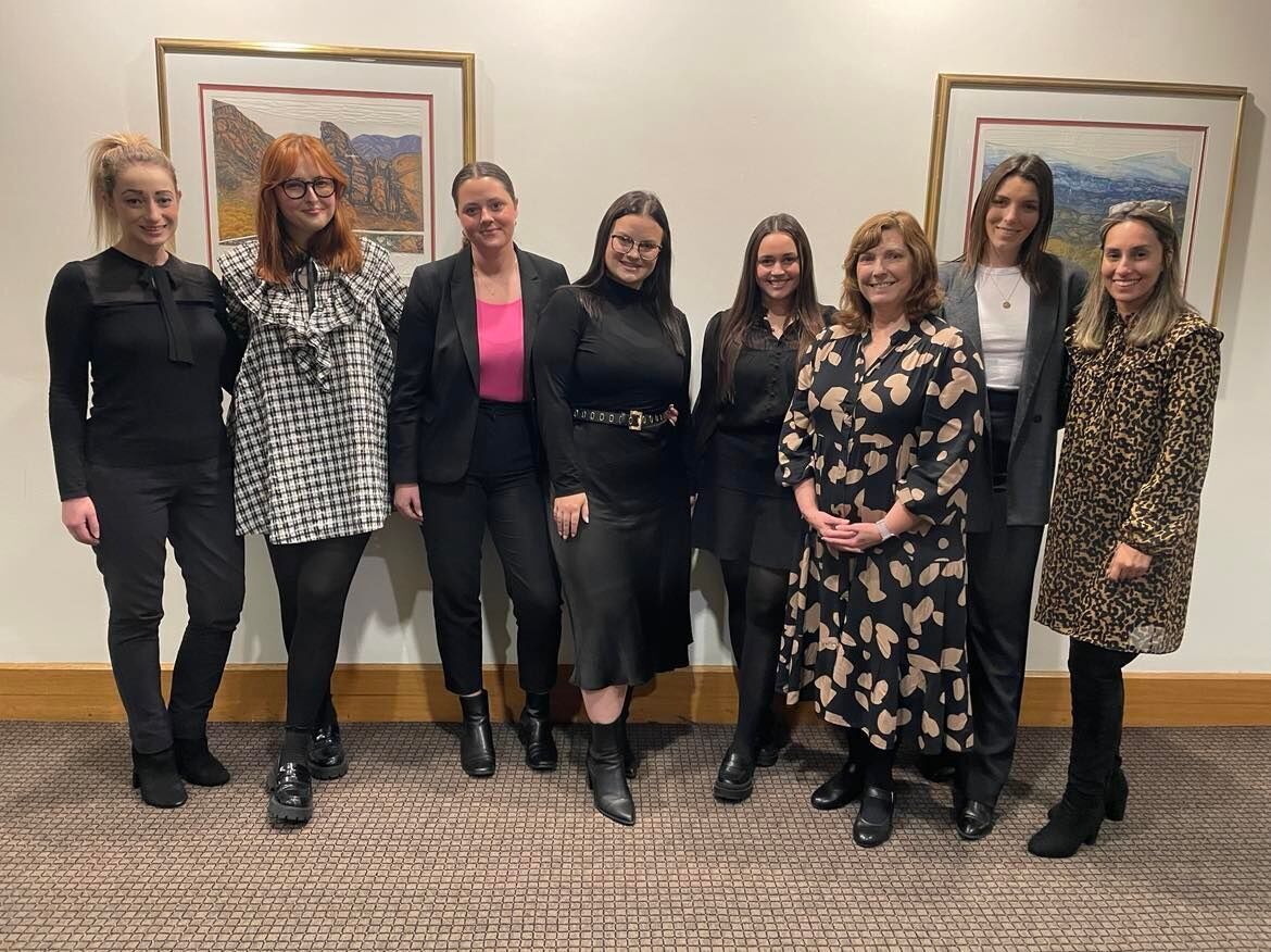 A group of women are posing for a picture in a room.