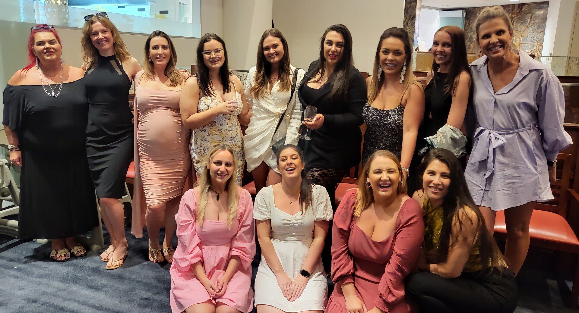 A group of women are posing for a picture together in a room.