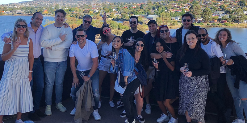 A group of people are posing for a picture in front of a body of water.