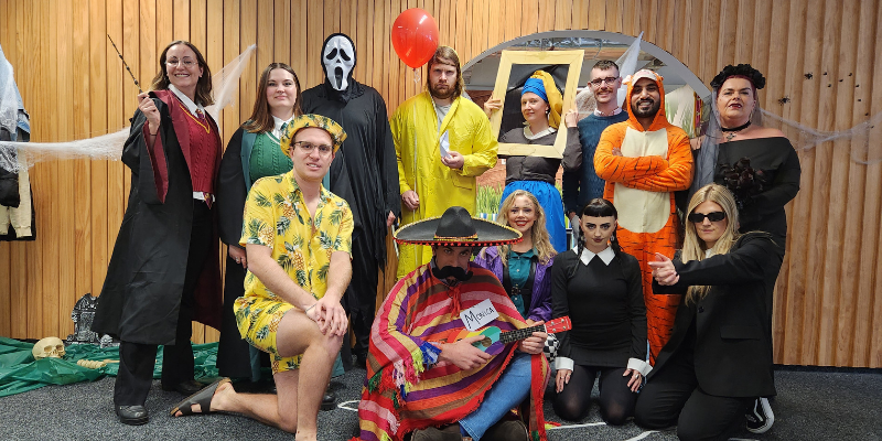 A group of people dressed in halloween costumes are posing for a picture.