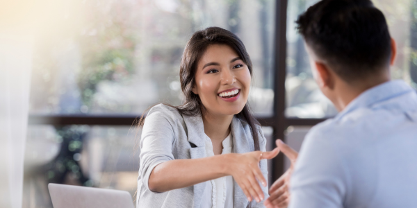 A woman is sitting at a table talking to a man.