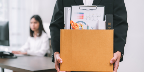 A man in a suit is holding a box of his belongings.