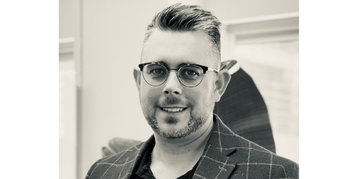 A black and white photo of a man wearing glasses and a suit.