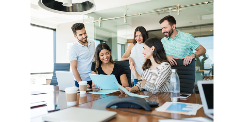 A group of people are sitting around a conference table looking at papers.