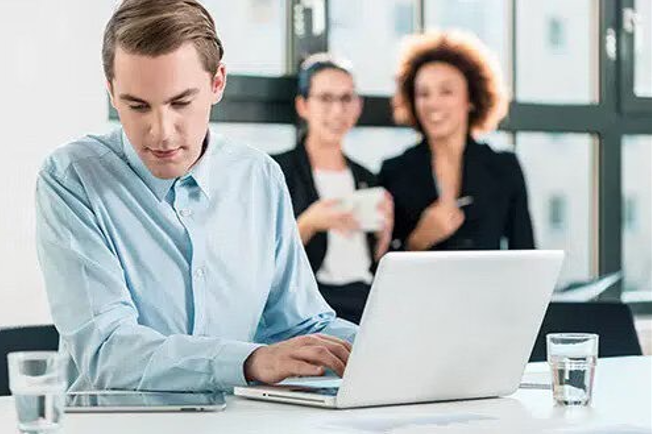 A man is sitting at a desk using a laptop computer.