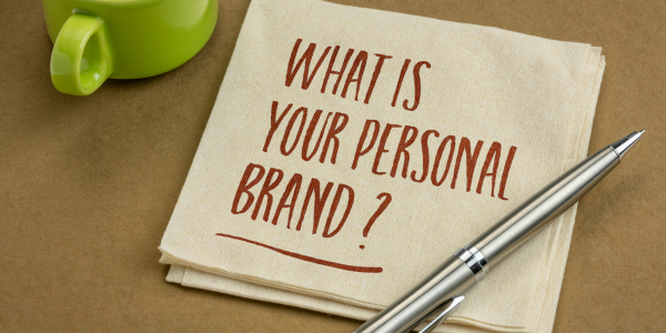 A napkin with the words `` what is your personal brand '' written on it next to a pen.