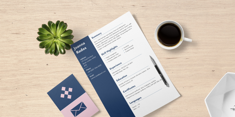 A resume is sitting on a wooden table next to a cup of coffee.