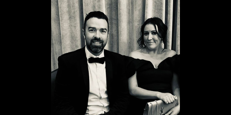 A man in a tuxedo and bow tie is sitting next to a woman in a black dress.