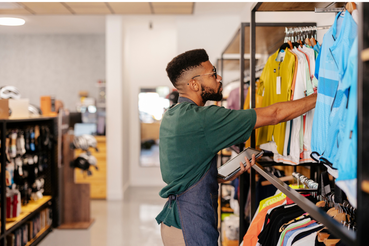 Person arranging colorful clothes on a store rack in a retail shop