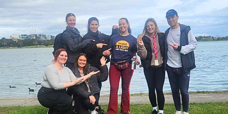 A group of people are posing for a picture in front of a body of water.