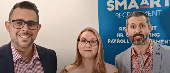 A man and a woman are standing next to each other in front of a sign.
