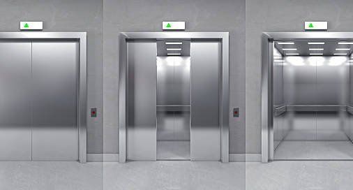 Three stainless steel elevators are lined up next to each other in a building.