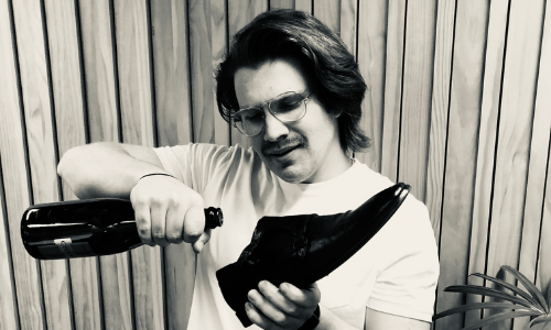 A man is pouring wine into a shoe in a black and white photo.