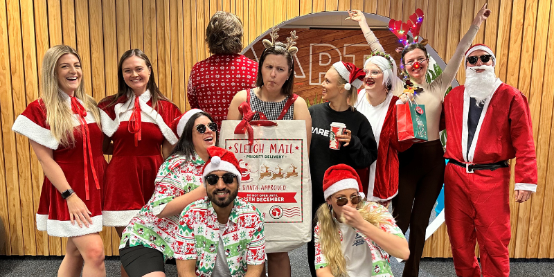 A group of people dressed in santa costumes are posing for a picture.