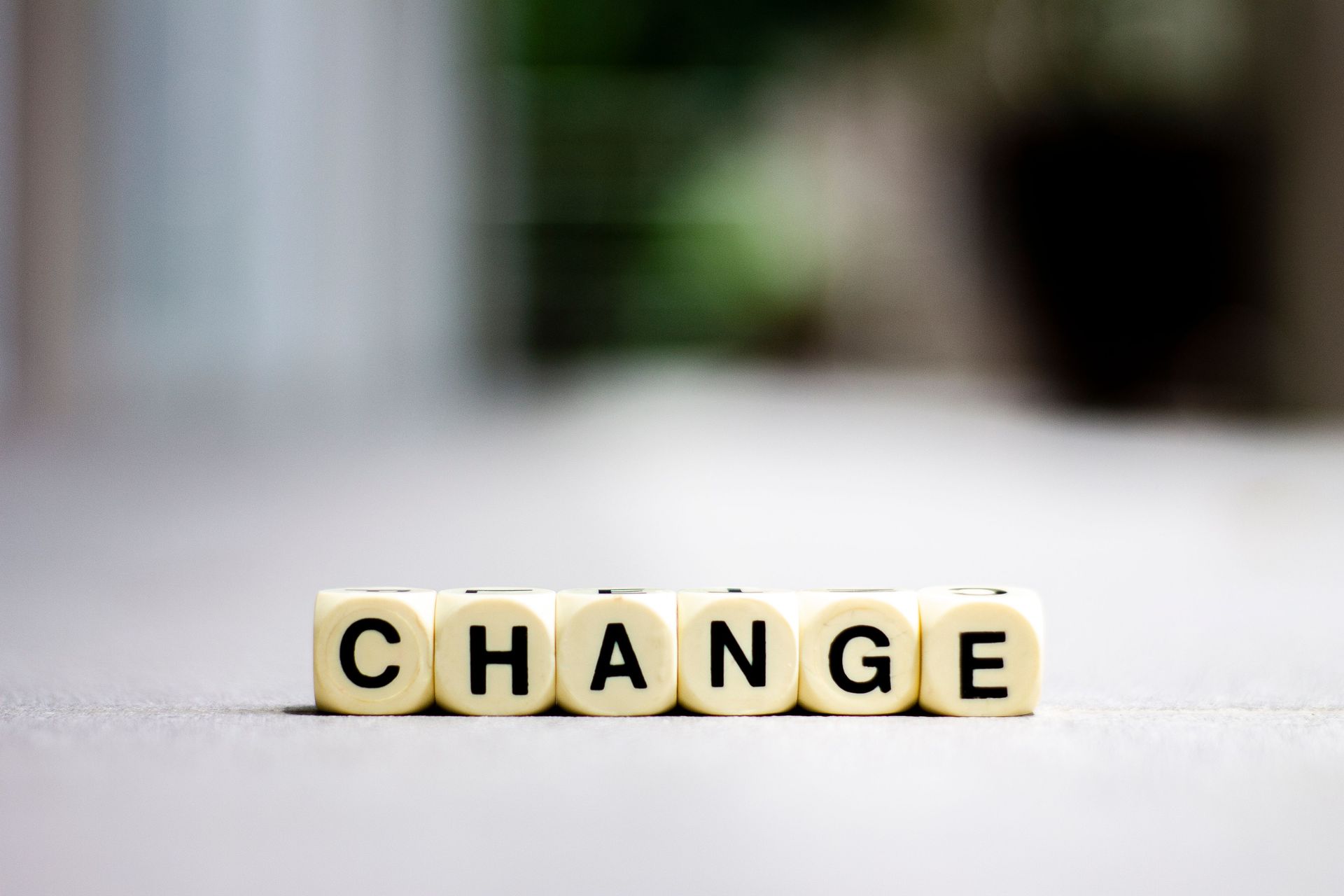 Letter tiles spelling “CHANGE” on a light surface with a blurred background.