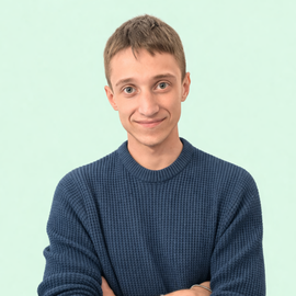 Persona sorridente con maglione blu e braccia incrociate su sfondo verde menta chiaro