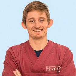 Persona sorridente con indosso una maglietta rossa e le braccia incrociate, su uno sfondo azzurro.