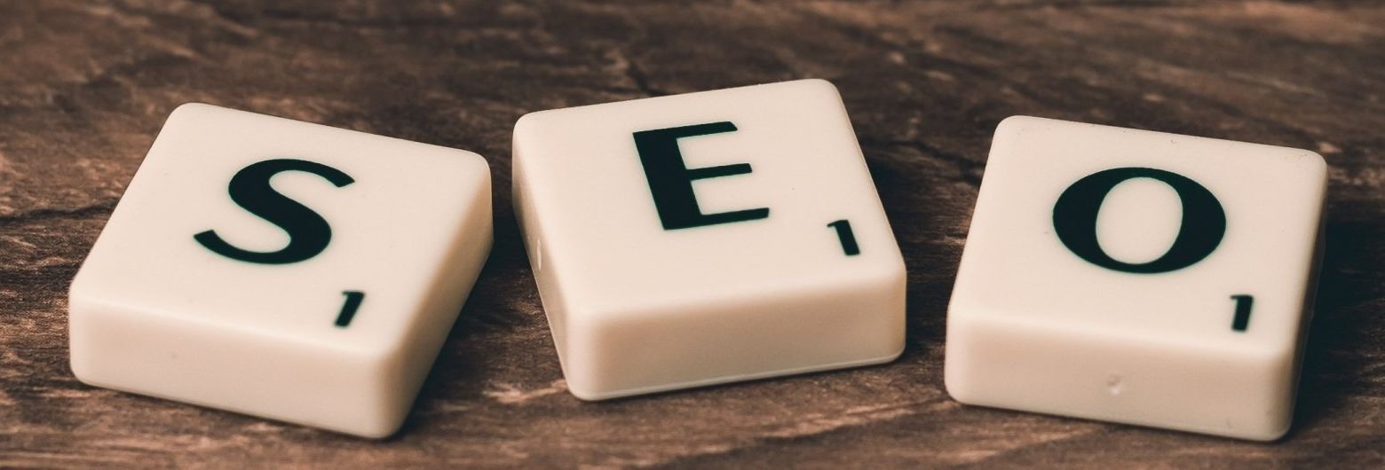 the word SEO is written on scrabble tiles on a wooden table.