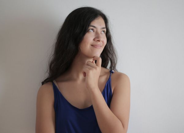 a woman in a blue tank top is thinking and smiling .