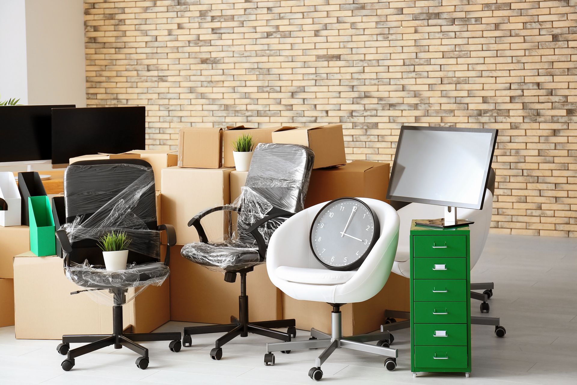 Office furniture and boxes in a moving scene, with chairs, desk items, and a green file cabinet