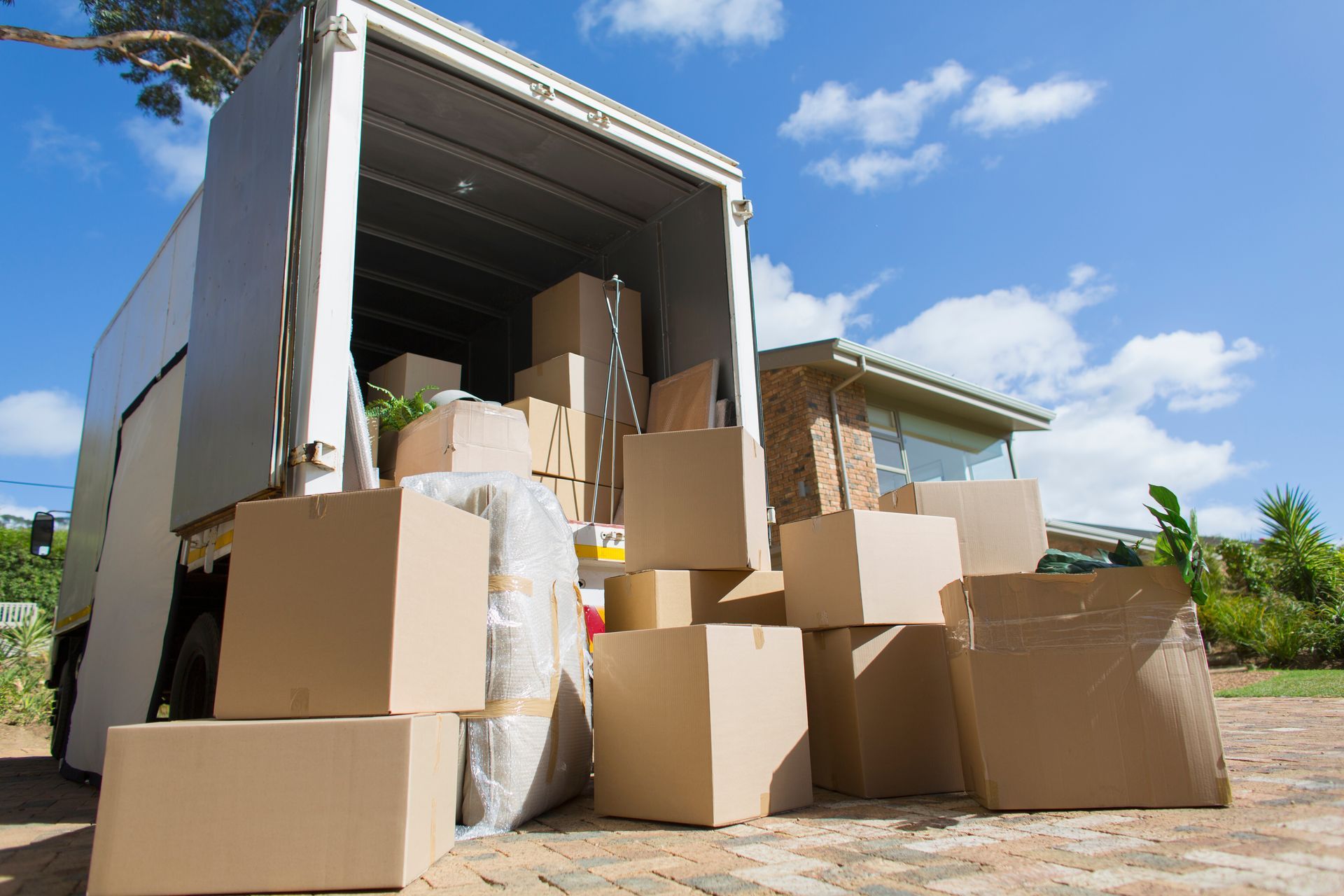 Open truck full of cardboard boxes on a sunny driveway