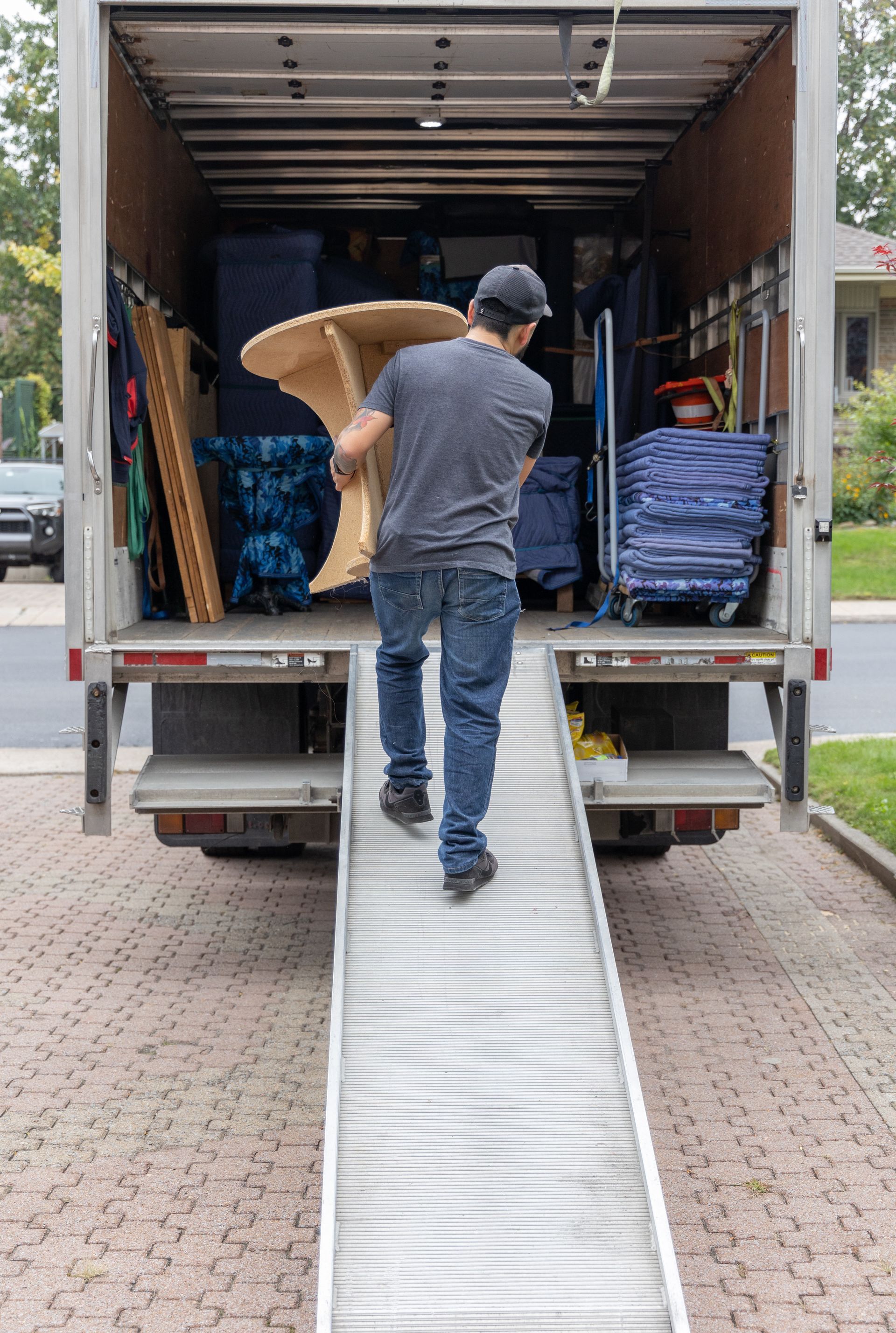 Person loading a large cardboard box up a ramp into a moving truck.