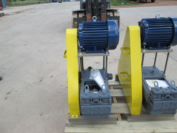 Two blue-and-yellow industrial machines on wooden pallets outdoors