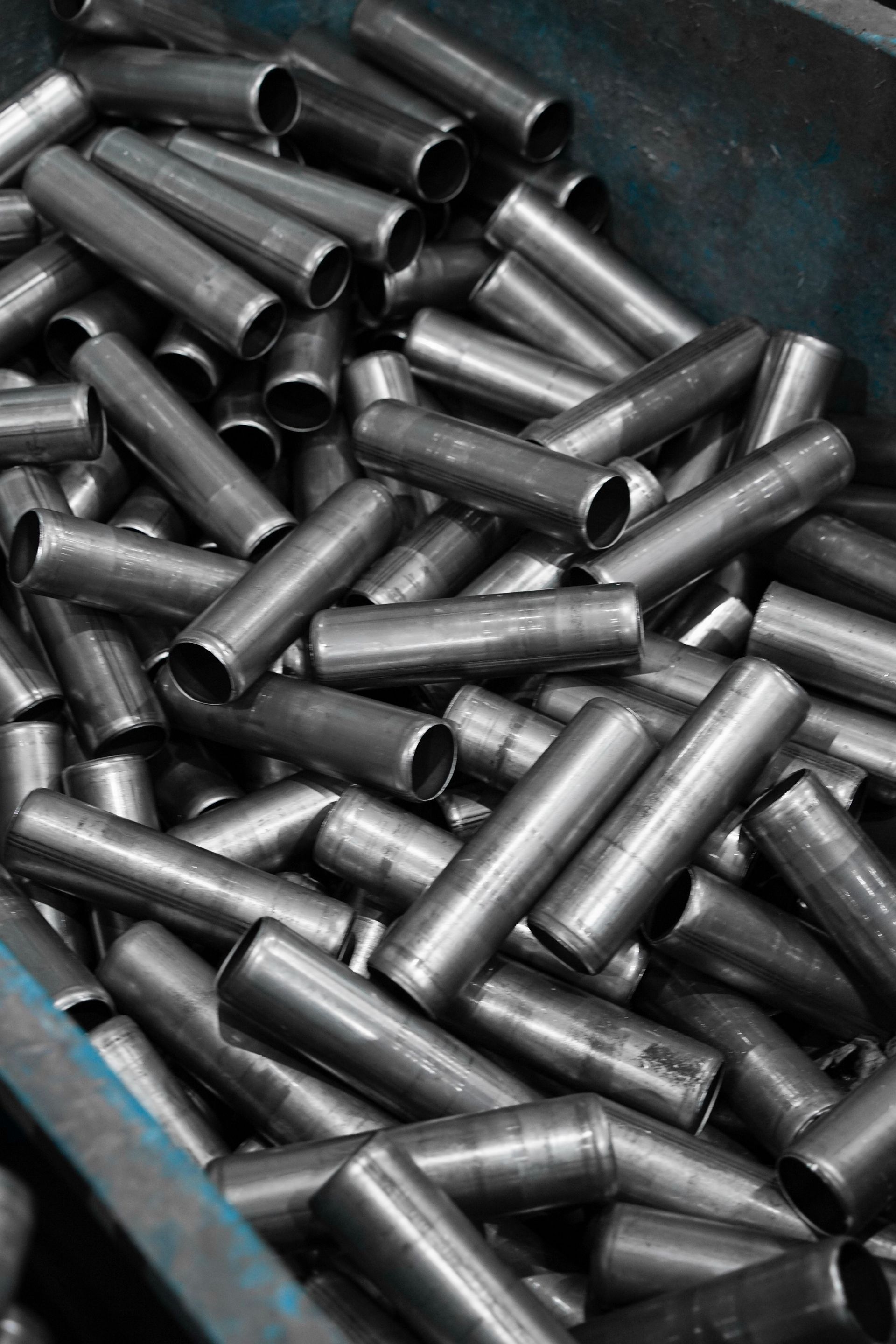 Pile of shiny metal pipes stacked in a bin