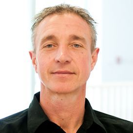 A man wearing a black shirt is looking at the camera