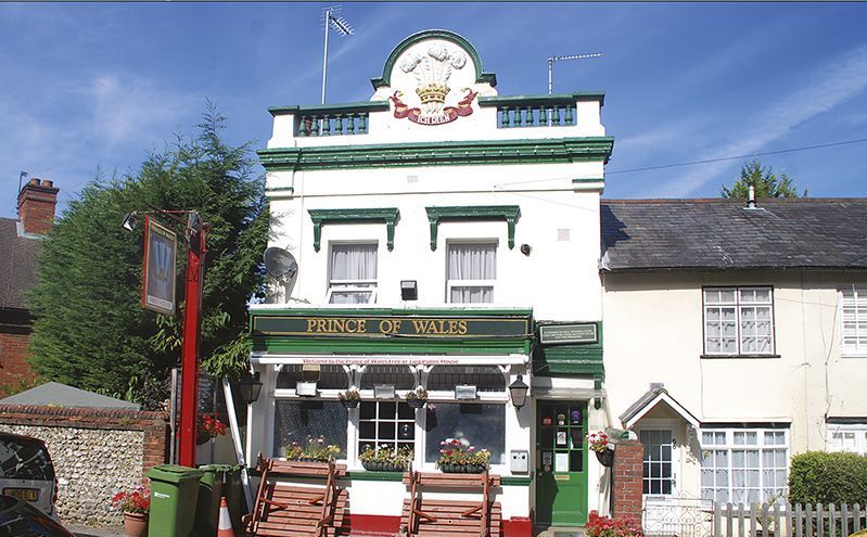 A white and green building with a sign that says ' crown of wales ' on it