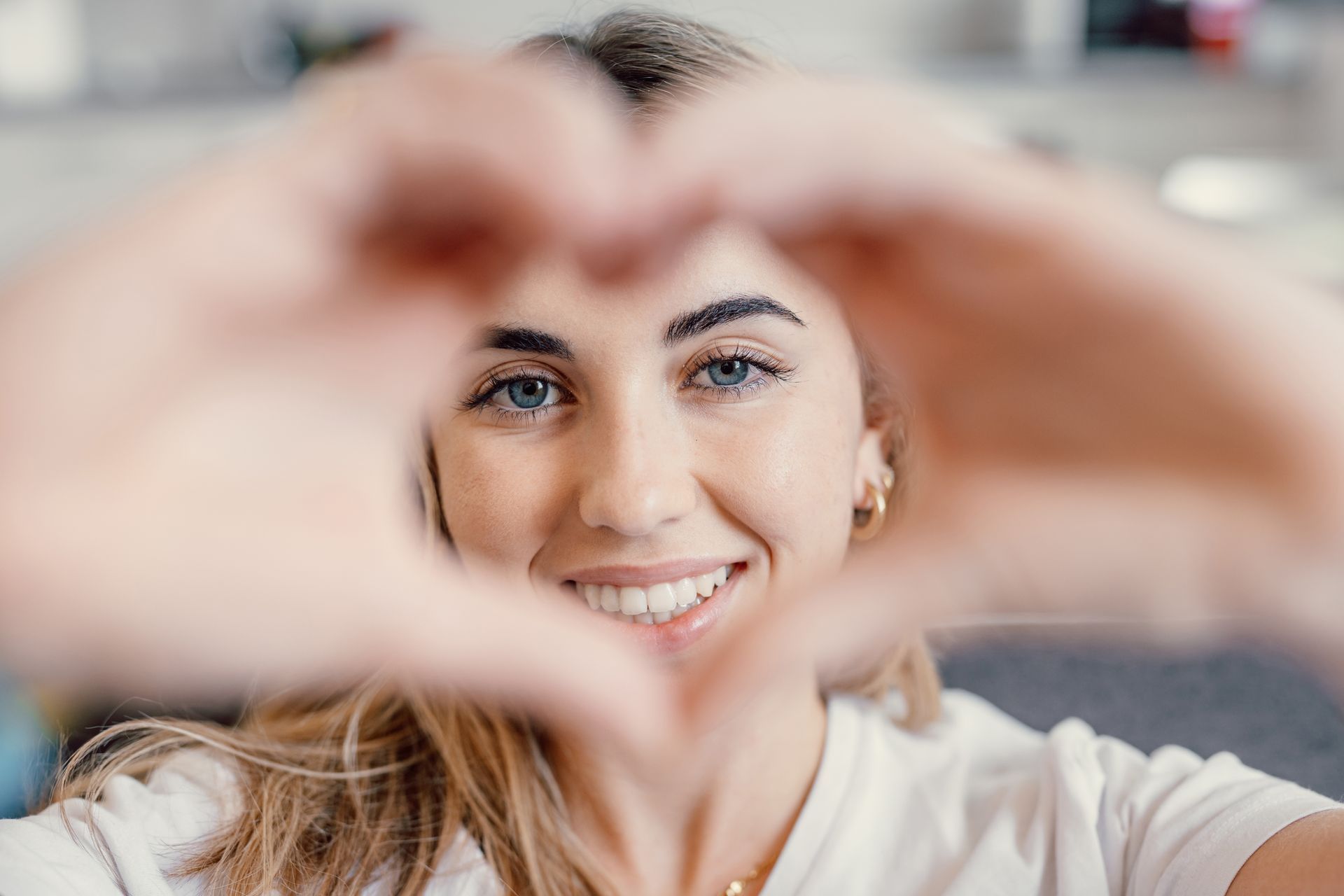 A woman is making a heart shape with her hands.