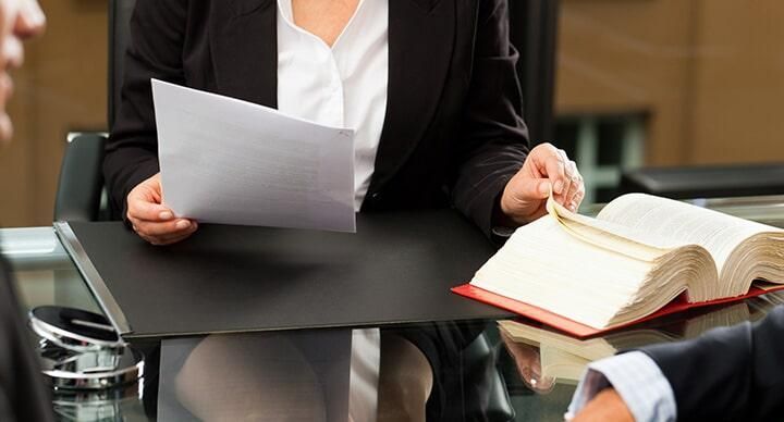 Una mujer está sentada en una mesa con un libro y un trozo de papel.