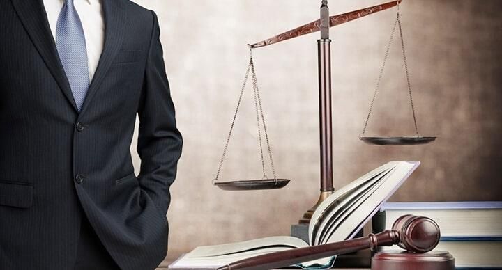 Un hombre con traje y corbata está de pie frente a una balanza de justicia.