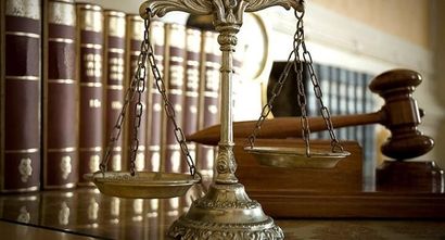 Una balanza de la justicia y un mazo están sobre una mesa delante de una fila de libros.