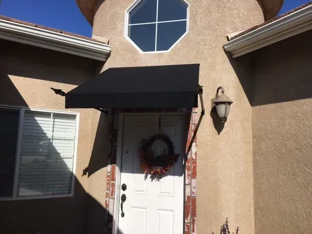 The front door of a house with a black awning over it