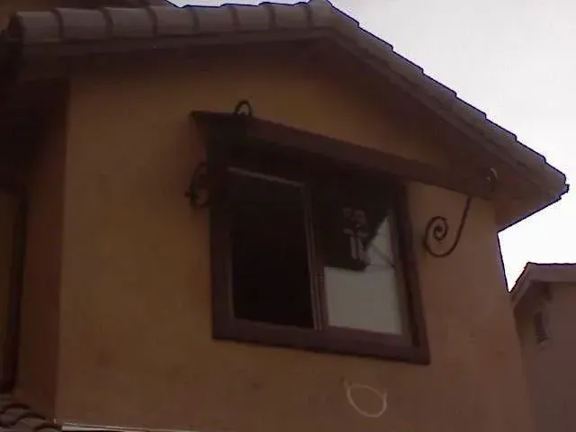 A window on the side of a building with a cross on it