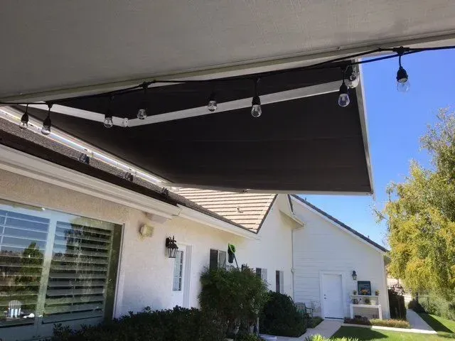 A white house with a black awning on the side of it.