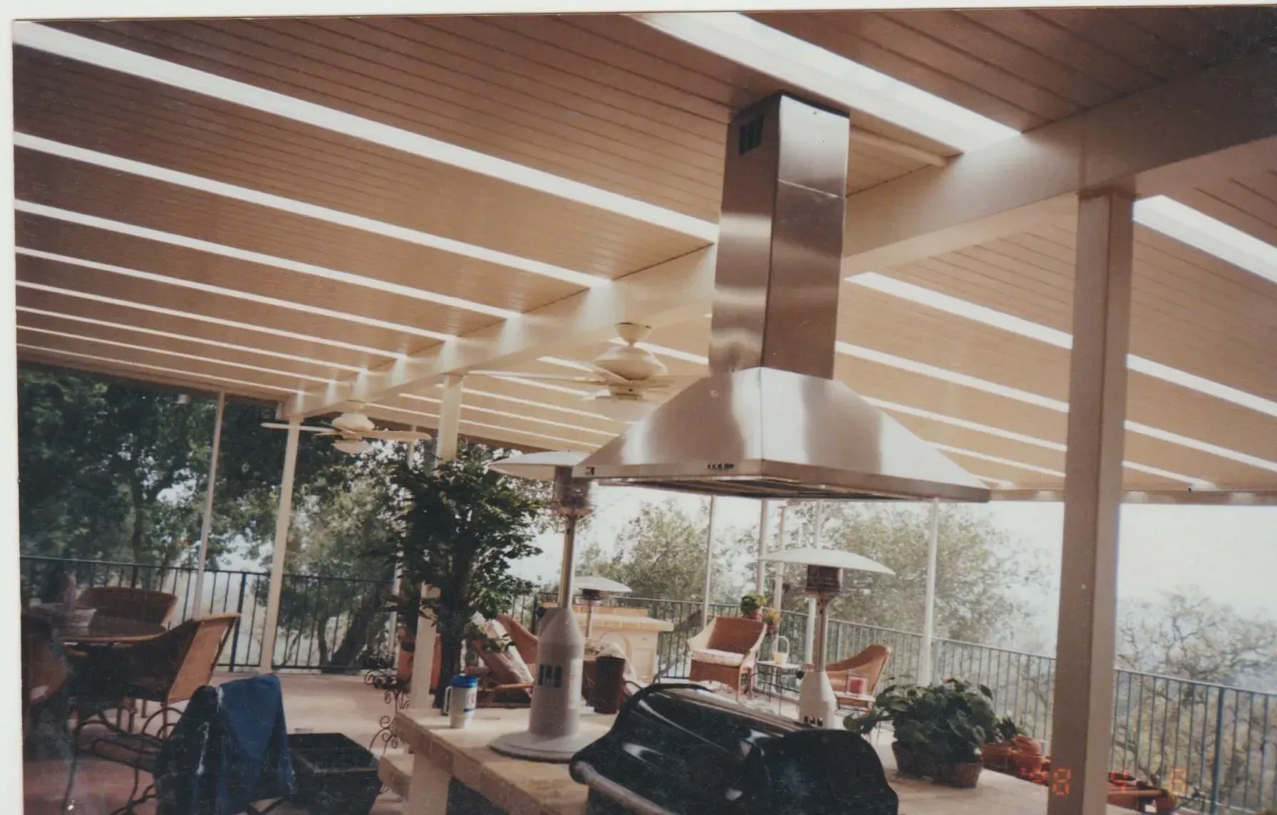 An outdoor kitchen with a stainless steel hood