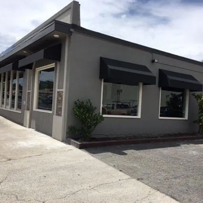 A gray building with black awnings on the windows A gray building with black awnings on the windows