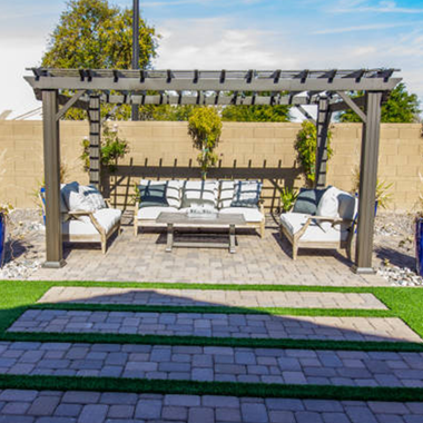 A patio with a pergola , couch , chairs and a coffee table. A patio with a pergola , couch , chairs and a coffee table.